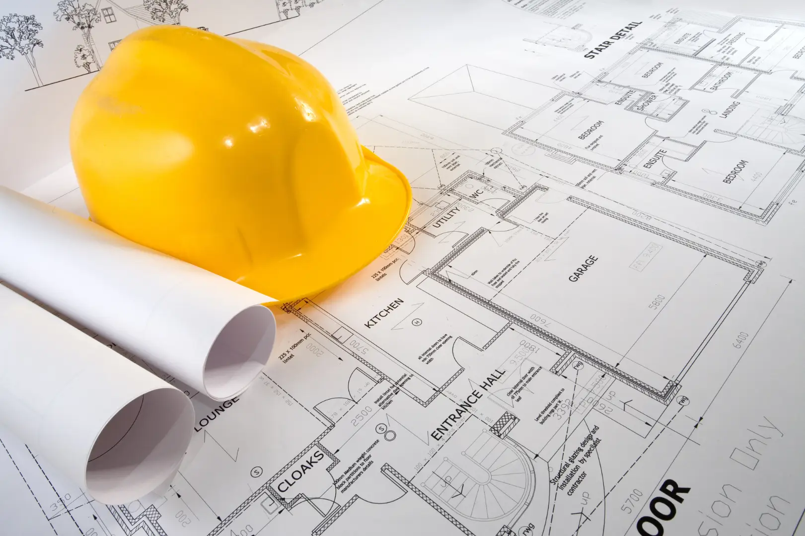 A yellow construction helmet on top of construction sketches.