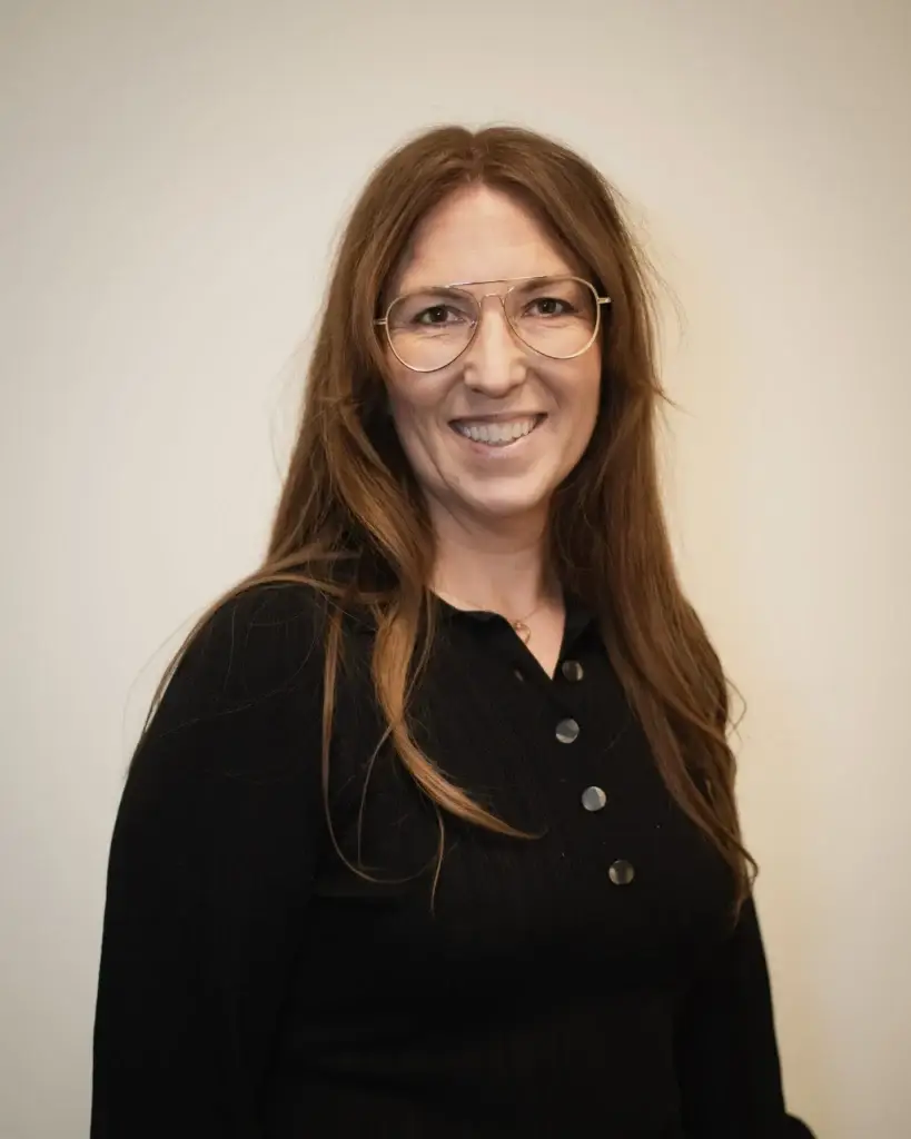 Helen Rigamonti standing in front of a white wall and amiling.