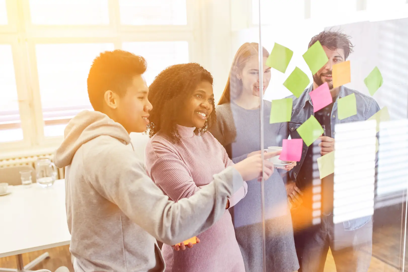 a team standing by a glass wall and moving around post-its in their workshop