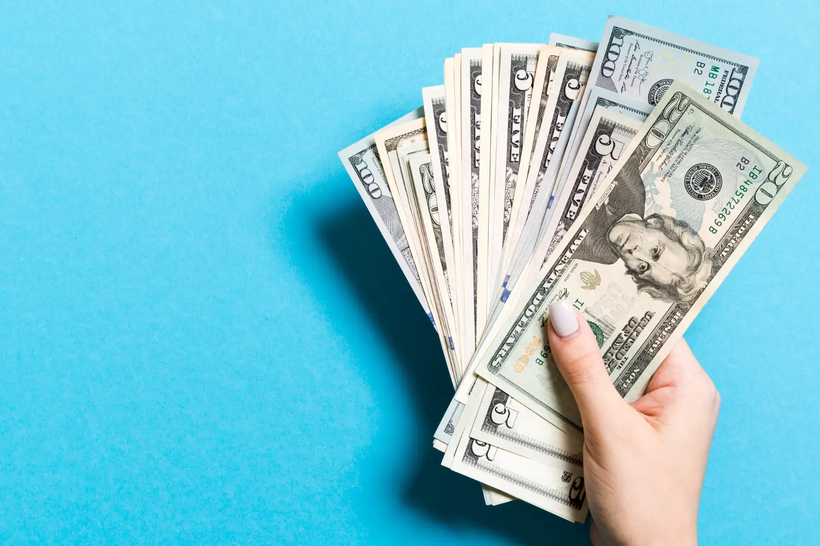 A hand holding cash as a sun feather in front of a blue background.