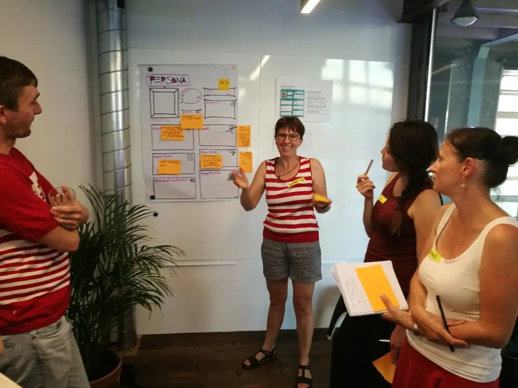 A team-lead showing her team the result from a workshop on a whiteboard.